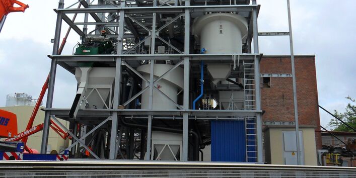 Anlage aus einem mehrstöckigen Metallgerüst mit Bottichen und Rohrleitungen, daneben ein Kran