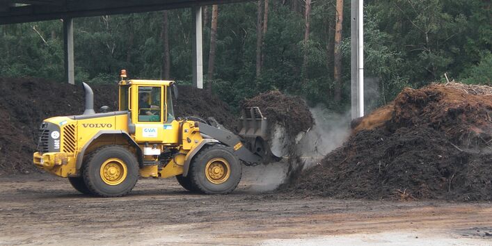 ein Radlader setzt einen großen Haufen Kompost um