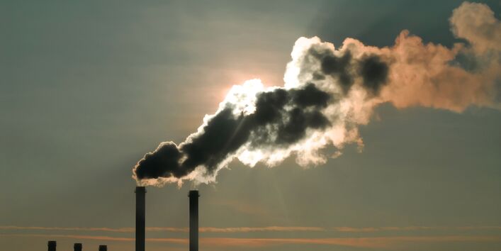 Smoke from chimney blocking the sun, hazy grey sky in background