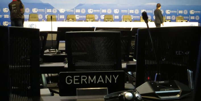 Saal mit Sitzreihen auf der COP27, auf einem Platz steht ein Schild "Germany", ein Mikrofon und ein Kopfhörer