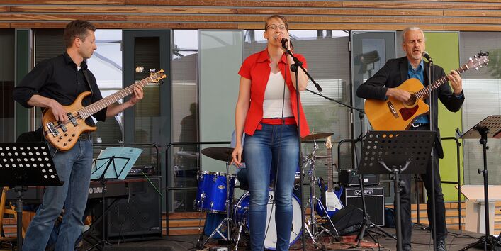 Band auf der Bühne mit einer Sängerin, einem Gitarristen, einem Bassisten und einem Schlagzeug