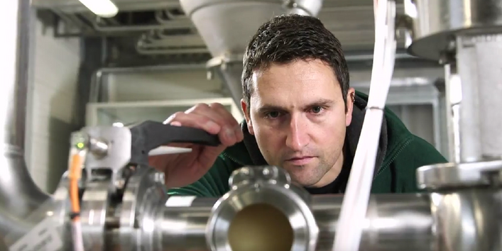 Ein Mann prüft eine Maschine in einer Werkshalle