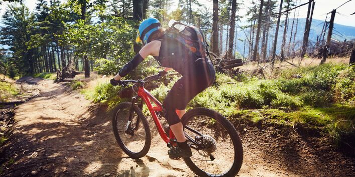 Mountainbike-Fahrerin mit Rucksack im Gelände