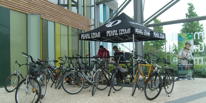 im Eingangsbereich des UBA-Dienstgebäudes Dessau werden Fahrräder repariert, im Hintergrund ein Werbeplakat für die Aktion "Mit dem Rad zur Arbeit"