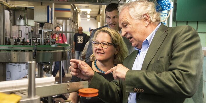 Bundesumweltministerin Schulze lässt sich die Flaschenwaschmaschine erklären