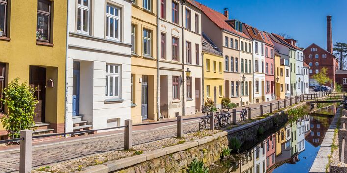 Häuserzeile mit verschiedenfarbigen Fassaden an einem Kanal in der Stadt