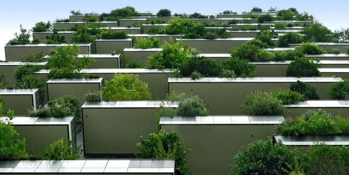 modernes Gebäude mit großen Balkonen mit Büschen und kleinen Bäumen