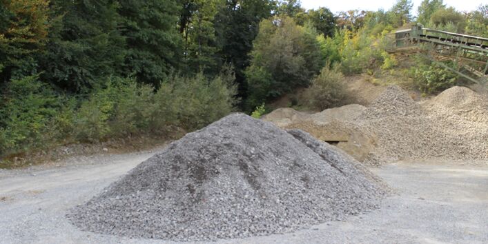 Im Vordergrund ein Haufen kleiner grauer Steine, im Hintergrund ein Haufen kleiner gelblicher Steine