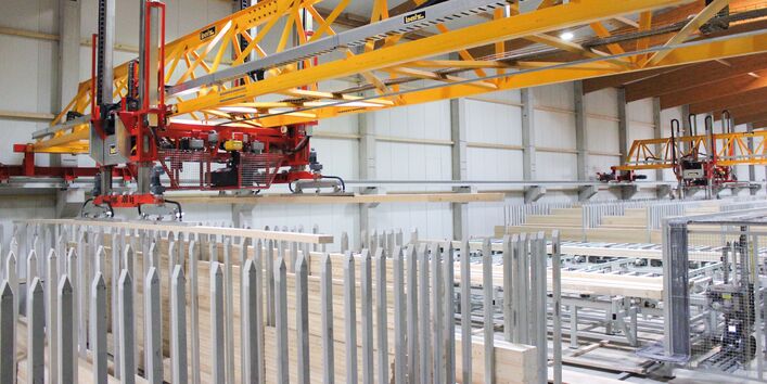 Lagerhalle, auf dem Boden lagern Holzbretter, darüber eine automatische Krananlage