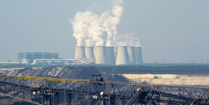 Kraftwerk Jänschwalde mit rauchenden Schloten, davor ein Braunkohletagebau