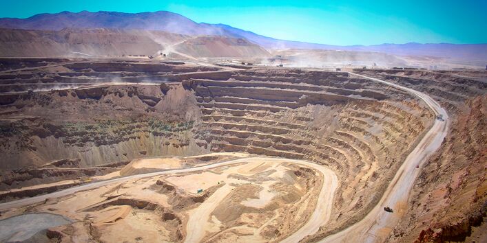 in einer bergigen, trockenen Landschaft klafft ein riesiges tiefes Loch mit terrassenförmigen Plateaus in der Erde