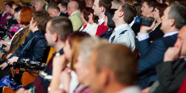 Zuhörer sitzen in einem Veranstaltungssaal in Stuhreihen