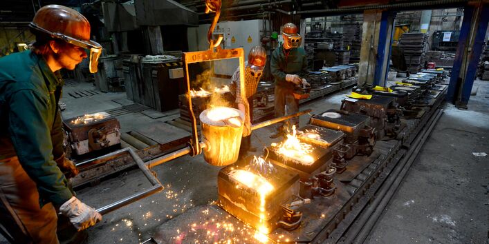 In einer Gießerei gießen Arbeiter flüssiges, glühendheißes Metall in Formen