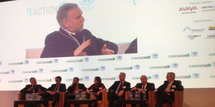 Jochen Flasbarth sitzt mit anderen Personen auf einem Podium, er redet und sein Bild wird vergrößert an die Wand projiziert