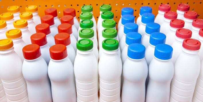 weiße, noch unbedruckte Plastikflaschen wie für Trinkjoghurt in einem Regal