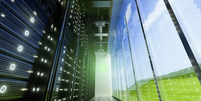 Blick in ein Rechenzentrum, durch eine Scheibe rechts des Gangs ist die grüne Umgebung zu sehen, links Serverschränke