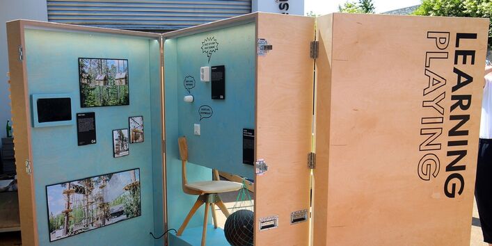 mannshohe Ausstellungsbox aus Holz auf Rollen, aufgeklappt sind Exponate zu sehen