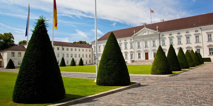 Eingang von Schloss Bellevue, der Weg ist von kegelfömig geschnittenen Gehölzen gesäumt