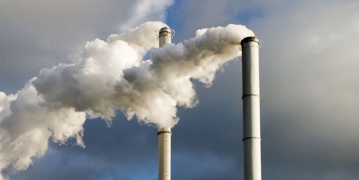 rauchende Schornsteine vor einem bewölkten Himmel