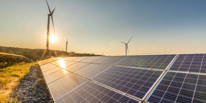 Ein Solarpark im Vordergrund ein Windpark im Hintergrund.
