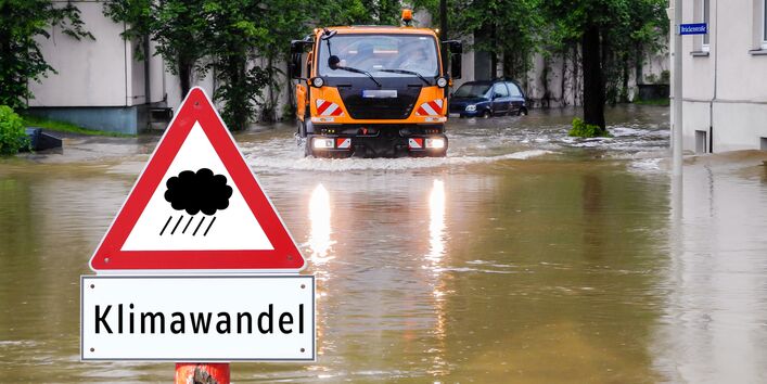 in einer überfluteten Straße in der Stadt steht ein Warnschild vor Starkregen durch Klimawandel