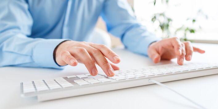 Mann tippt auf einer Tastatur