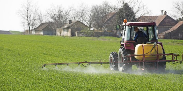 ein Traktor spritzt Pestizide auf einem Feld