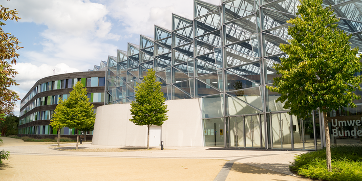modernes Bürogebäude mit viel Glas, davor Bäume, am Eingang Schriftzug Umweltbundesamt