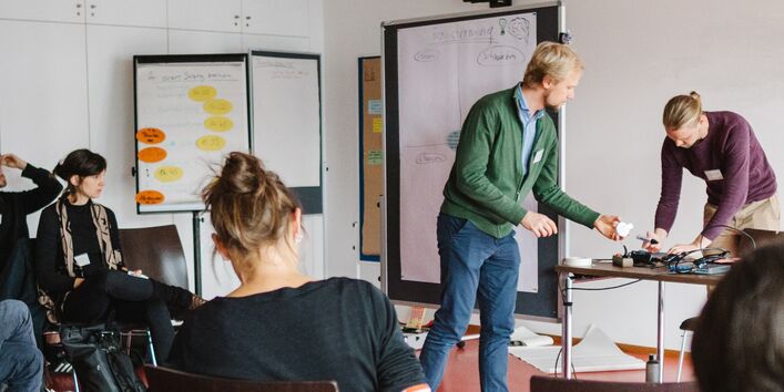 fünf Personen in einem Raum mit Flipcharts