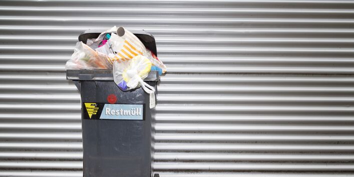 überquellende Restmülltonne auf einem Gehweg