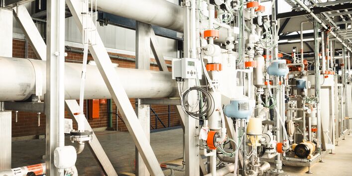 Anlage mit vielen Rohrleitungen in einer Werkshalle