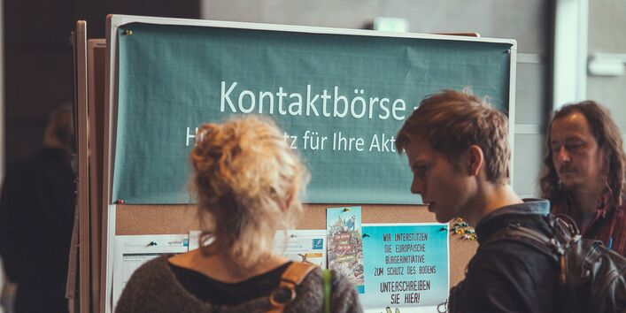 Teilnehmer vor einer Informations-Pinnwand