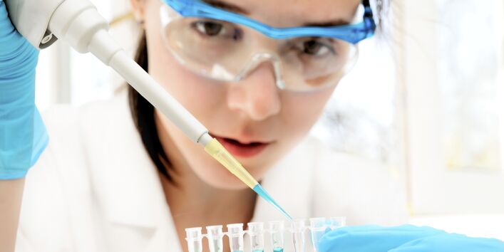 Junge Chemielaborantin füllt Flüssigkeitsproben ab.