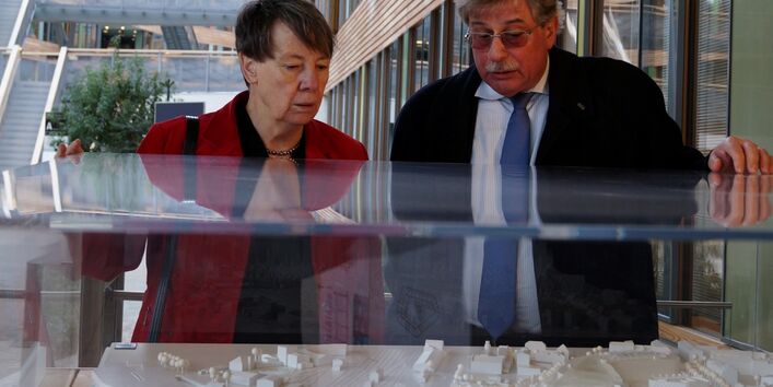 Barbara Hendricks und UBA-Vizepräsident Holzmann stehen an einer Vitrine und betrachten ein Modell des UBA-Gebäudes in Dessau-Roßlau.