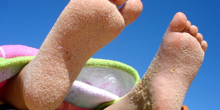 Sandige Kinderfüße vor blauem Himmel