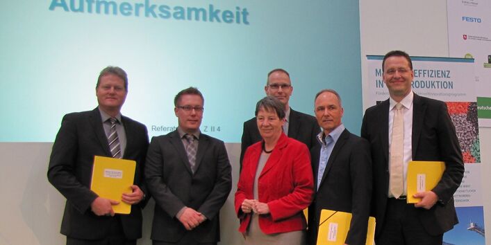 Bundesumweltministerin Hendricks und fünf Herren in Anzügen stehen lächelnd auf einer Bühne, drei Herren haben gelbe Mappen unter dem Arm, im Hintergrund ein Plakat zum Umweltinnovationsprogramm