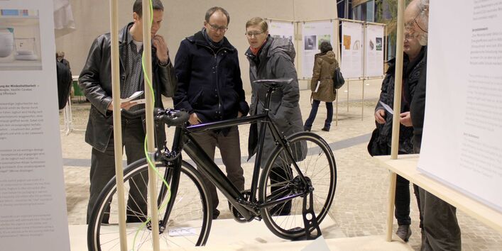 Besucher der Wanderausstellung sehen sich das ausgestellte Elektrofahrrad im Atrium im UBA Dessau an.