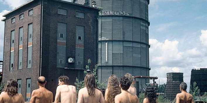 nackte Gruppe von Menschen mit Blickrichtung weg vom Betrachter, in Richtung eines Hauses blickend