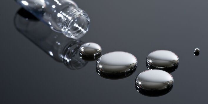 Sechs Quecksilbertropfen fließen aus einem Glasgefäß