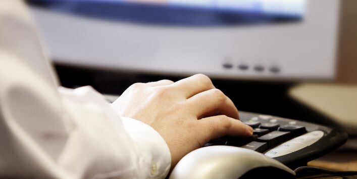 Großaufnahme einer Hand, die auf einer Tastatur tippt