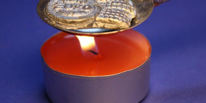 red candle with a spoon for lead pouring