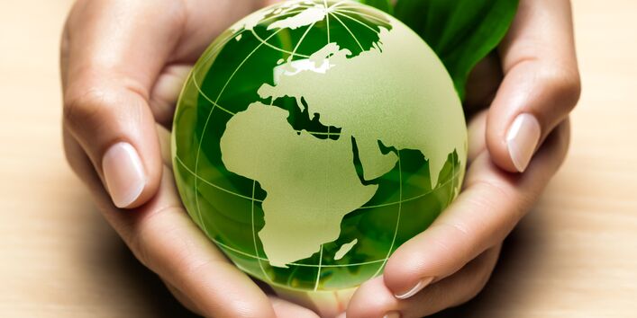 Zwei Hände halten die grüne Erdkugel
