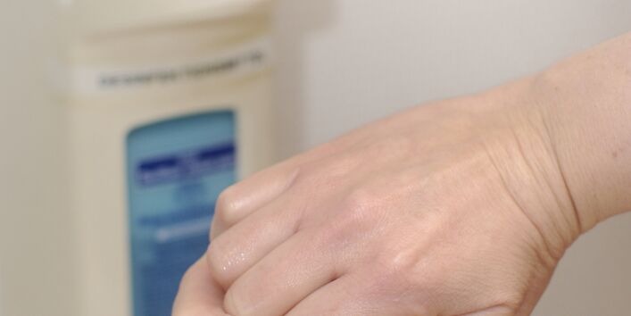 Hände verreiben das Desinfektionsmittel aus dem Spender.