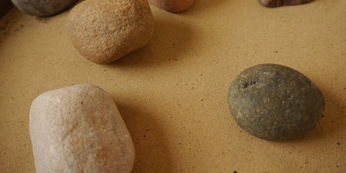 Steine liegen auf hellem Sand.