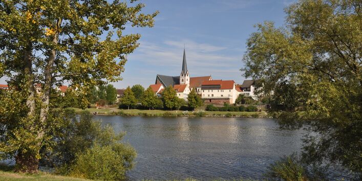 Kleinstadtansicht mit Kirchturm, im Vordergrund See