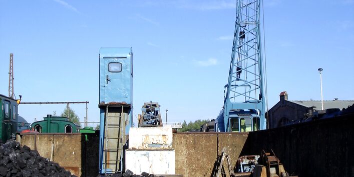 Steinkohleberg am Bahnhof zur Beladung alter Dampfloks, die im Hintergrund zu sehen sind