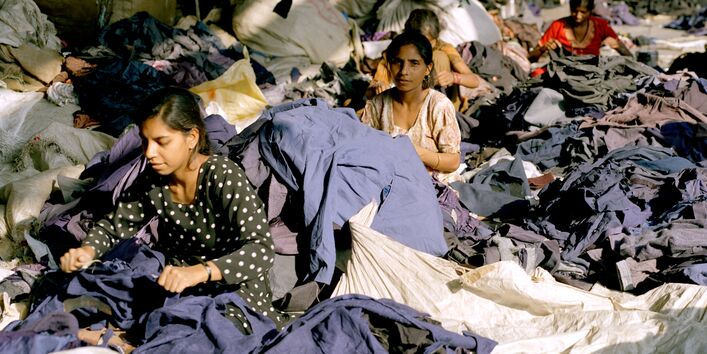 Frauen zerschneiden Jacken und Oberteile; die eingenähten Etiketten werden herausgeschnitten - Marken und Labelsangaben werden bei dem Prozess wertlos.
