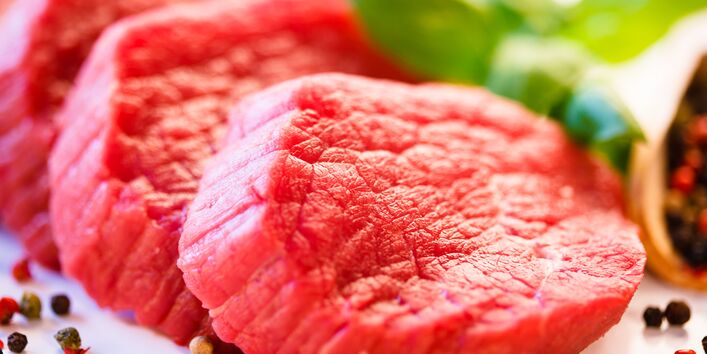 Drei Scheiben rohes Rindfleisch, umgeben von buntem Pfeffer und Deko