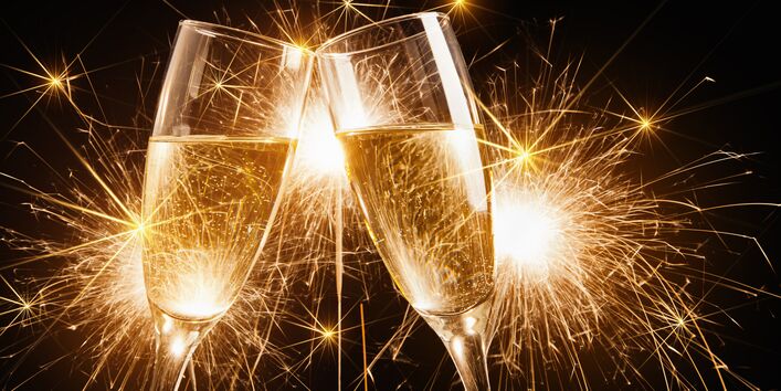 zwei Sektgläser vor goldenem Feuerwerk