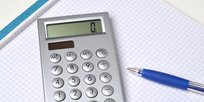 solarbetriebener Taschenrechner und ein Kugelschreiber auf einem Schreibblock